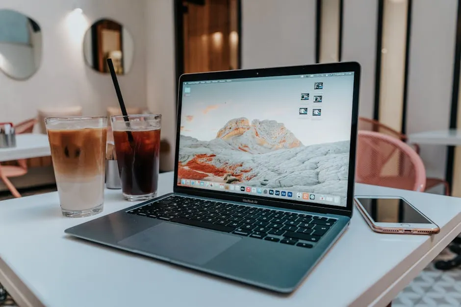 MacBook Air على طاولة بيضاء بجانب قهوة مثلجة في مقهى